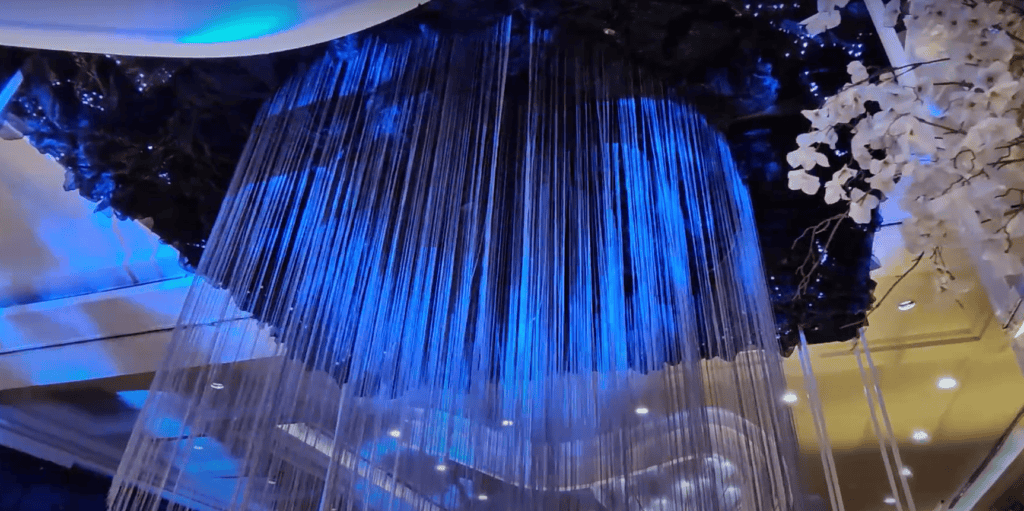 Hanging crystal strands illuminated in blue on wedding gazebo ceiling