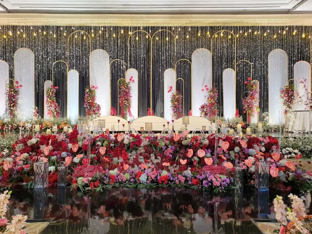 Grand wedding stage with red and fuchsia flowers, styled by Trinity Artwork