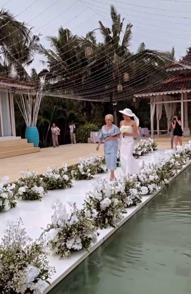 Hannah Sinclair walks a floral-lined aisle at her Bali wedding